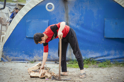 A syrian refugee boy chops firewood in the cold weather in refugee camps.