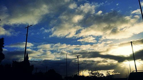 Low angle view of power lines against cloudy sky