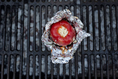 A top view shot of a red bell pepper filled with cheese on a grill outdoors