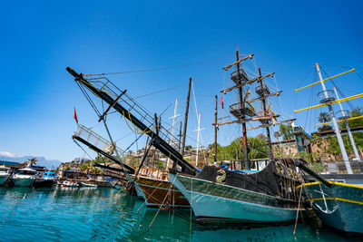 Boats in sea against clear blue sky