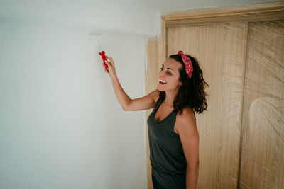 Happy woman standing against wall at home