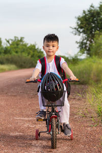 Full length portrait of boy riding bicycle on road against sky