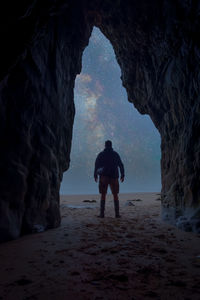 Rear view of man standing on rock in sea