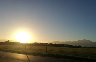 Scenic view of field against clear sky at sunset