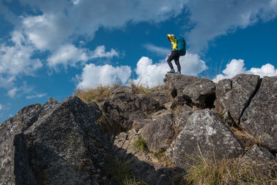 Low angle view of woman standing on cliff against sky