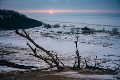 Scenic view of snow covered land against sky during sunset