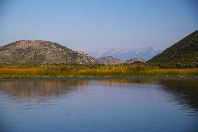 Scenic view of lake by mountains against clear sky