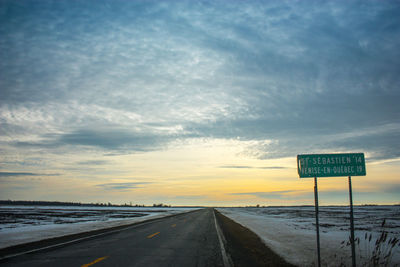 Road sign against sky during sunset