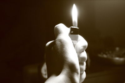 Close-up of hand holding lit candle