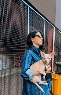 Portrait of young woman standing by fence