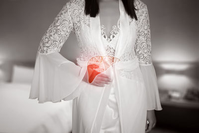 Midsection of woman holding umbrella standing against white background