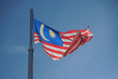 Low angle view of malaysian flag against blue sky