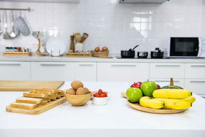 Sandwich preparation in kitchen. wholewheat bread, eggs, tomatoes, vegetable, and fruit. 