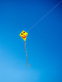 Low angle view of kite flying against clear blue sky