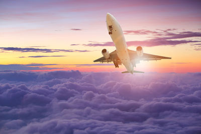 Low angle view of airplane flying against sky during sunset