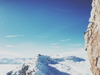 Low angle view of snowcapped mountains against blue sky