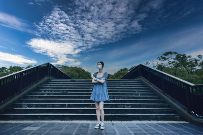 Full length of woman standing on staircase against sky