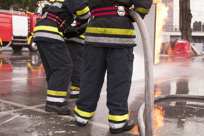 Low section of firefighters standing on wet road