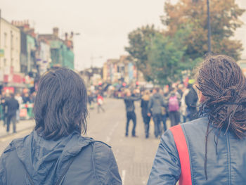 Rear view of people walking on street in city