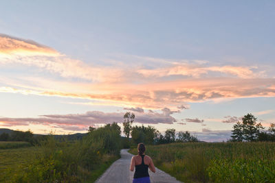 Rear view of woman running on road against sky
