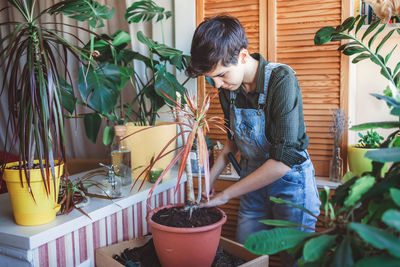Happy young girl repotting home plants on the balcony, green environment in room, home gardening