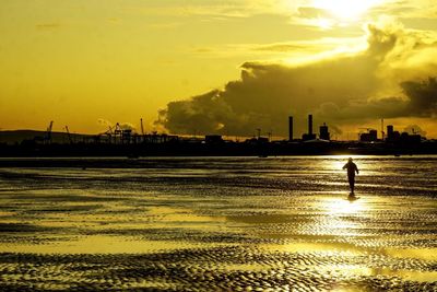 Silhouette person on beach against sky during sunset