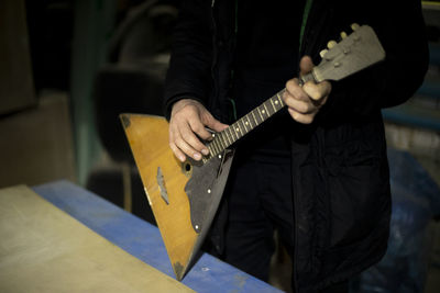 Midsection of man playing guitar