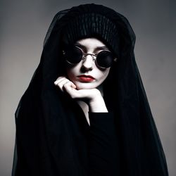 Portrait of beautiful woman wearing sunglasses against gray background