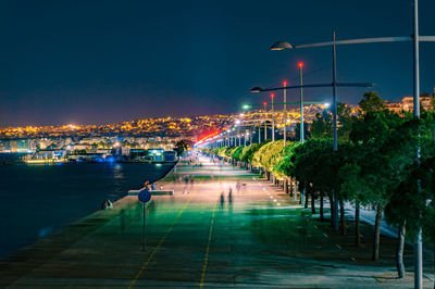 Illuminated city street against sky at night