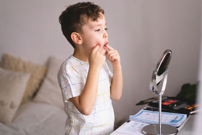 Boy pronouncing sound o looking at mirror doing an online speech therapy lesson through a laptop