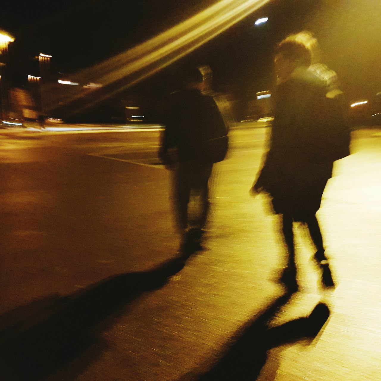 BLURRED PEOPLE WALKING ON ILLUMINATED STREET AT NIGHT