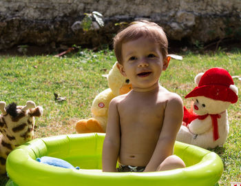 Cute toddler boy sitting in wading pool at back yard
