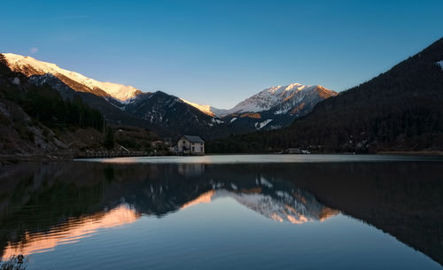 Scenic view of lake by mountains against sky during winter