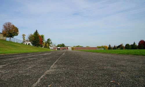 Road amidst field against sky