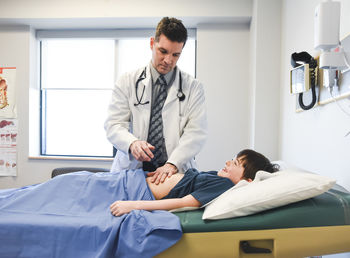 Doctor examining abdomen of child on an exam table of a clinic.