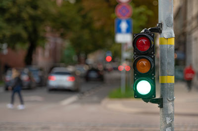 Blurred view of city traffic with traffic lights, in the foreground a semaphore with a green light