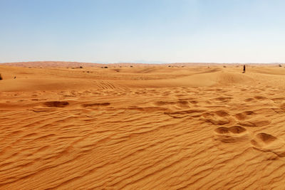 Scenic view of desert against clear sky on sunny day