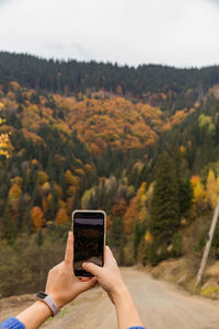 Midsection of man using mobile phone against plants