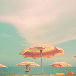 Low angle view of beach umbrella against cloudy sky on sunny day