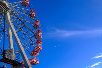 Rollercoaster wheel and plane trails on blue sky background 