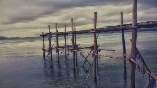 Wooden posts on beach against sky