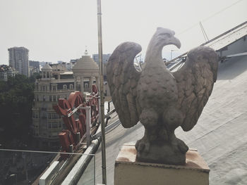 Statue in city against sky