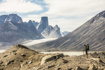 Backpacker in rugged landscape looking out at mountain view.