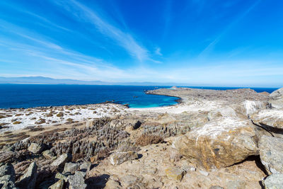 Rocks on field by sea against blue sky at isla damas island