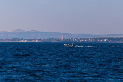 Boat sailing in sea against clear sky