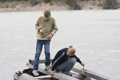 Siblings on damaged wooden raft at river