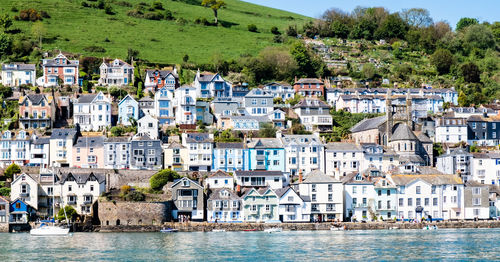 Buildings by sea against trees in city