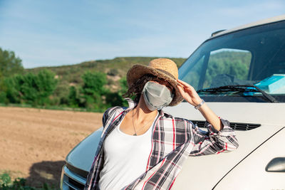 Portrait of woman wearing mask while standing by vehicle
