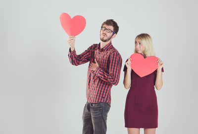 Young couple holding heart shape over white background