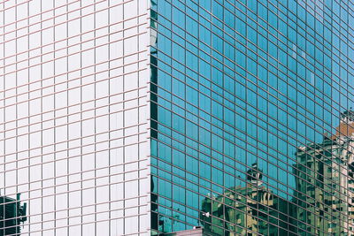Low angle view of reflection in modern glass building in the city